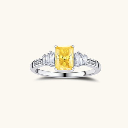 Sterling silver ring with emerald-cut yellow moissanite center stone and clear baguette side stones in elegant setting
