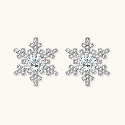 Sterling silver snowflake stud earrings with brilliant moissanite centers and intricate geometric patterns on cream background