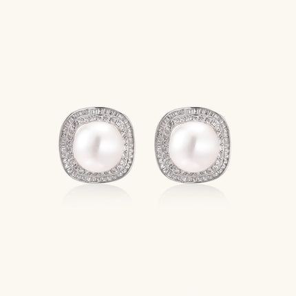 Rhodium-plated sterling silver stud earrings with round freshwater pearls surrounded by geometric crystal halos on cream background.