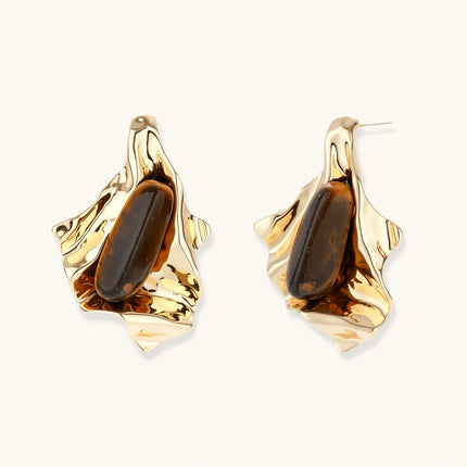 Sculptural stud earrings with organic twisted metal design holding brown gemstones, shown in gold and silver finishes.