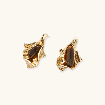 Sculptural stud earrings with organic twisted metal design holding brown gemstones, shown in gold and silver finishes.