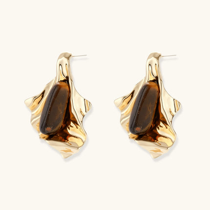 Sculptural stud earrings with organic twisted metal design holding brown gemstones, shown in gold and silver finishes.