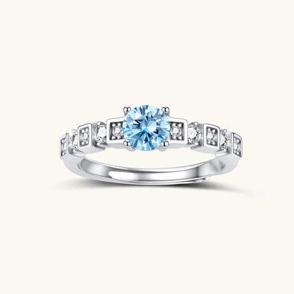 Geometric sterling silver ring with light blue moissanite center stone and square diamond accents on white background