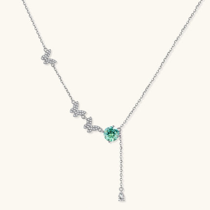 Sterling silver necklace with butterfly charms, green moissanite center stone, and teardrop crystal pendant on white background.