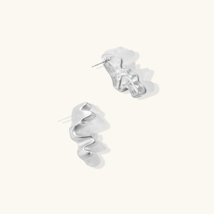Pair of silver-toned sculptural earrings with flowing abstract forms and stud backs against white background.