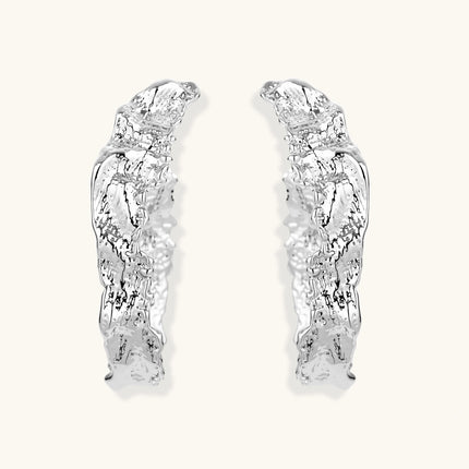 Close-up of textured silver hoop earrings with twisted rope-like pattern and post-back closure on white background.