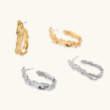 Close-up of textured silver hoop earrings with twisted rope-like pattern and post-back closure on white background.