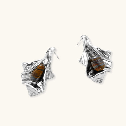 Silver sculptural earrings with flowing molten forms and amber gemstones, featuring 925 silver posts on white background.