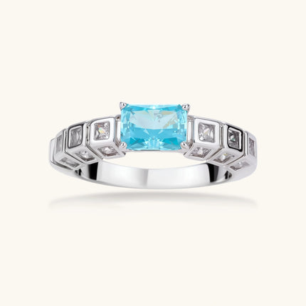 Geometric silver-plated ring with rectangular aqua cubic zirconia center and square crystal details on adjustable band.
