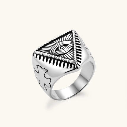 Silver stainless steel signet ring with engraved all-seeing eye in triangle, radiating lines, and cross motifs on the band.