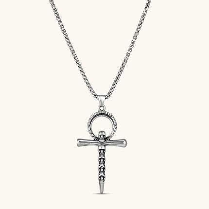 Silver stainless steel ankh pendant with skull motifs on vertical bar and textured ring top, on a box chain necklace.