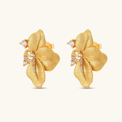 Gold-plated 925 silver flower stud earrings with brushed finish, swirl detail, and pavé cubic zirconia on cream background.